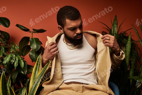Preview: Handsome young man in summer fashion poses among lush greenery indoors