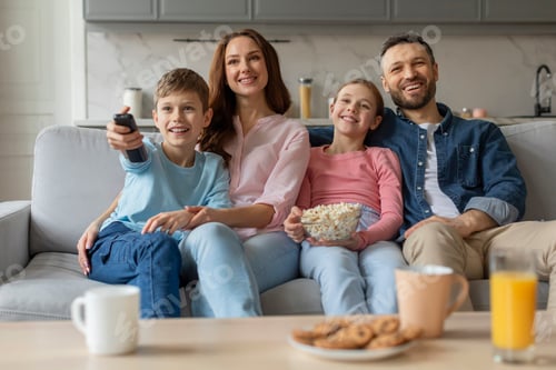 Preview: Family watching TV together, smiling joyfully at home