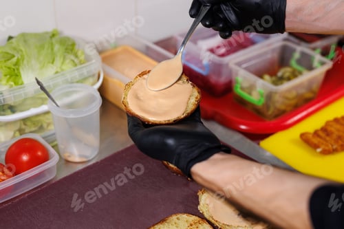 Preview: Cooking a burger on the grill. Spreading sauce on a burger bun.