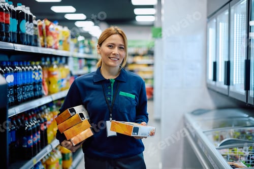 Preview: Smiling supermarket employee working at frozen food compartment and looking at camera.