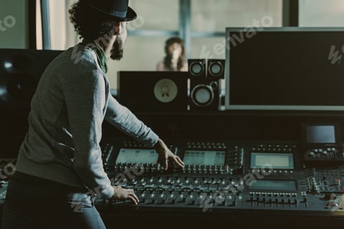 Preview: back view of sound producer in hat recording song at studio