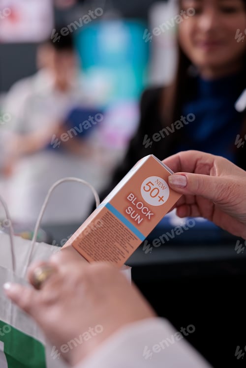 Preview: Pharmacy cashier selling sunblock and putting product in bag