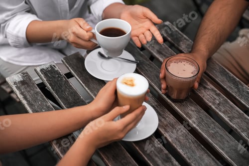 Preview: Friends drinking coffee and cocoa at wooden table in outdoor cafe, closeup