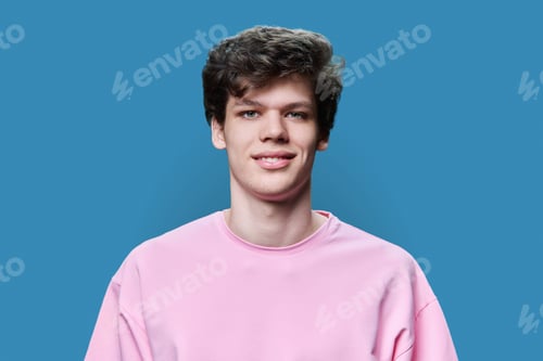 Preview: Headshot portrait of young smiling guy looking at camera on blue background