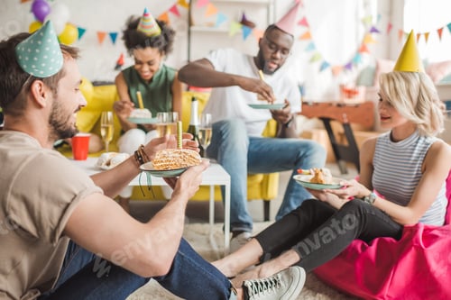 Preview: Multiracial smiling friends having party with birthday cake