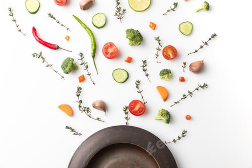 Preview: Top view of black plate and cut vegetables isolated on white
