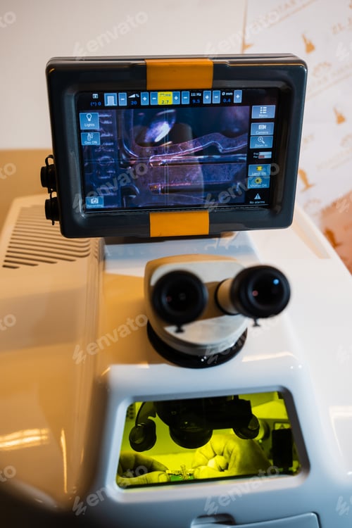 Preview: Jeweler performing precision laser soldering of gold jewelry parts under a microscope.