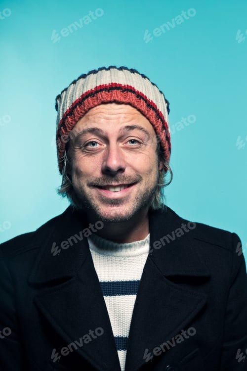 Preview: Studio Portrait Of Young Casual Man With Long Blond Hair Wearing Woolen Winter Cap And Black