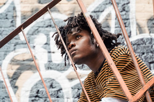 Preview: Portrait of young handsome stylish black man with natural hair dreadlocks. Afroamerican guy. Stairs,