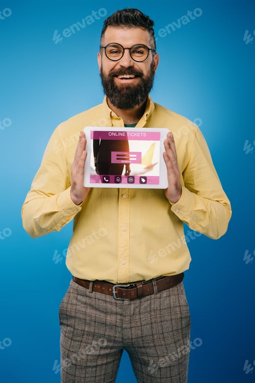 Preview: smiling bearded man presenting digital tablet with online tickets app, isolated on blue