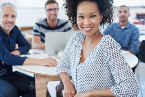Preview: Portrait of a young office worker sitting at a table with colleagues in the background