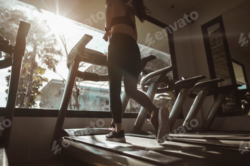 Preview: Women walking on the treadmill in the gym for good health and strength at sunset.