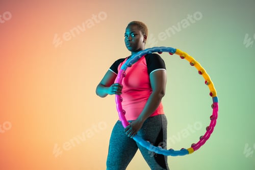 Vista previa: Young african-american plus size female model's training on gradient background