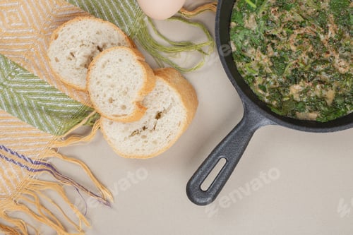 Preview: A dark pan with omelet , greens and white fresh bread