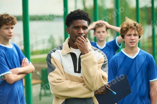 Preview: Black Man Coaching Diverse Teenagers during Outdoor Soccer Practice