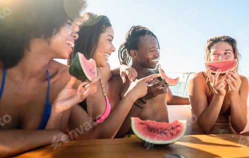Preview: Group of multicultural young having a tour on boat and eating fresh watermelon