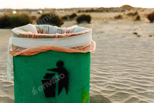 Preview: Green waste container on sandy beach. Plastic waste pollution and greenwashing