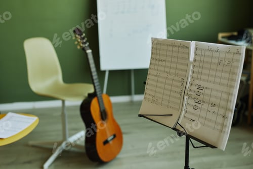 Preview: Two papers with musical notes on music stand on background of guitar