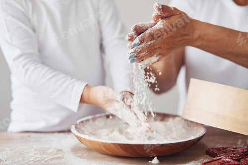 Preview: Close up view of woman with her granddaughter preparing food with flour on kitchen