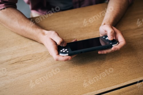 Preview: Cropped man holding digital joypad press handheld buttons for win virtual 3s game,