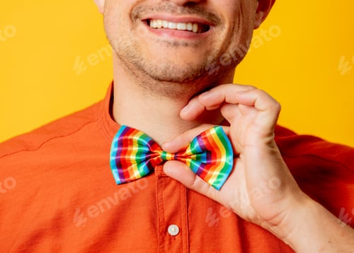 Preview: Smiling Man with Rainbow Bowtie Against Yellow Background