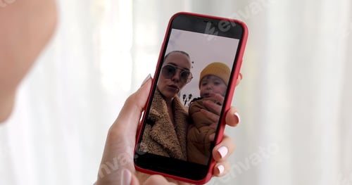 Preview: Woman hand with smartphone showing kid picture