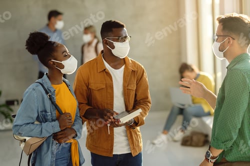 Preview: College students wearing protective face masks while talking in a lobby.