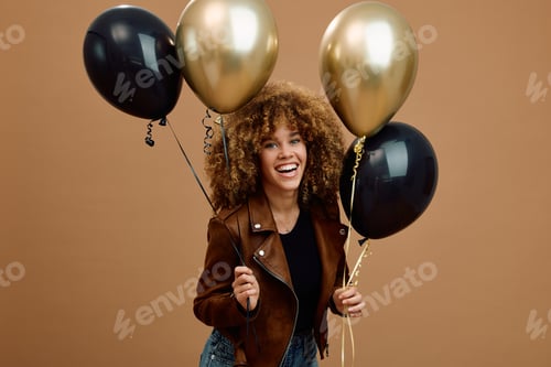 Preview: Cheerful woman with black and golden balloons looking at camera.