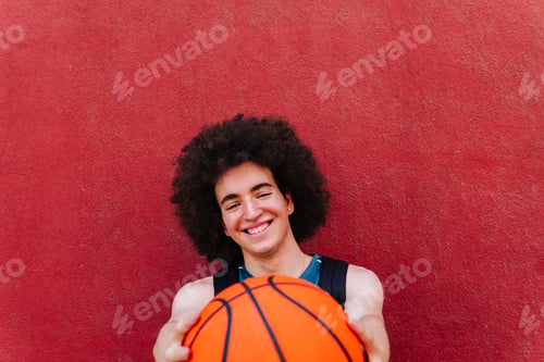Preview: Basketball player holding a ball and smiling at camera