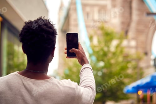 Preview: Male Vlogger Or Social Influencer In London Taking Photo On Mobile Phone Of Tower Bridge
