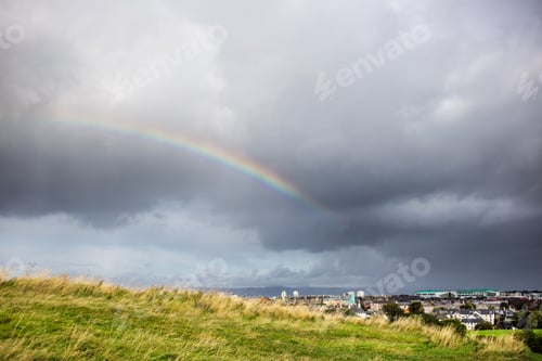 Preview: cloudy sky and rainbow above the city