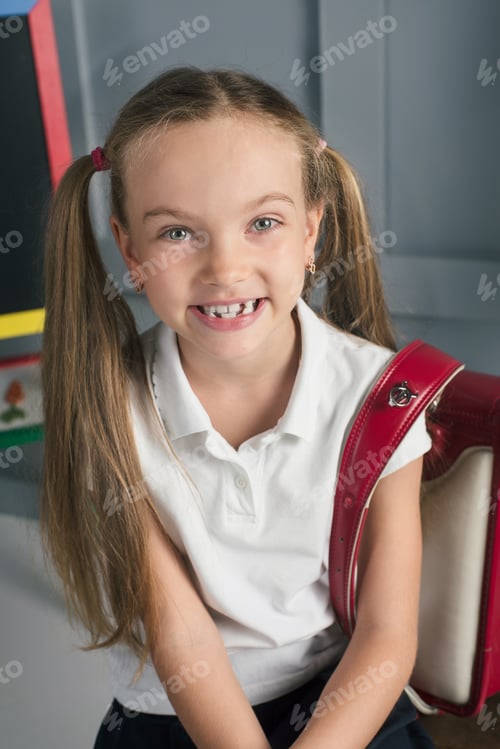 Preview: Happy schoolchild in the classroom with big backpack