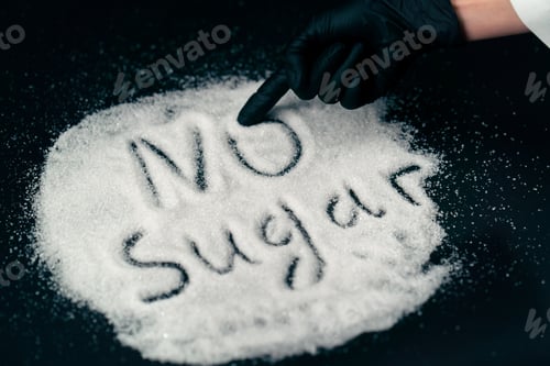 Preview: close-up on black-blue background on white crumbly granulated sugar lies crystal female hand writes