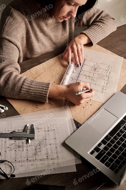 Preview: Young contemporary engineer or architect with ruler and pen looking at sketch