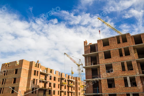 Preview: Construction site of a new apartment high building with tower cranes against blue sky.