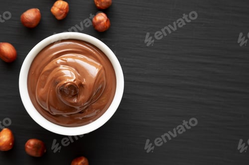 Preview: Homemade Chocolate Hazelnut Spread in a Bowl on a black background, top view. Flat lay, overhead