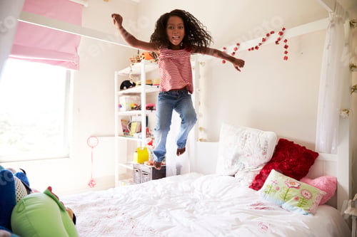 Preview: Young Girl Having Fun Jumping On Bed In Bedroom