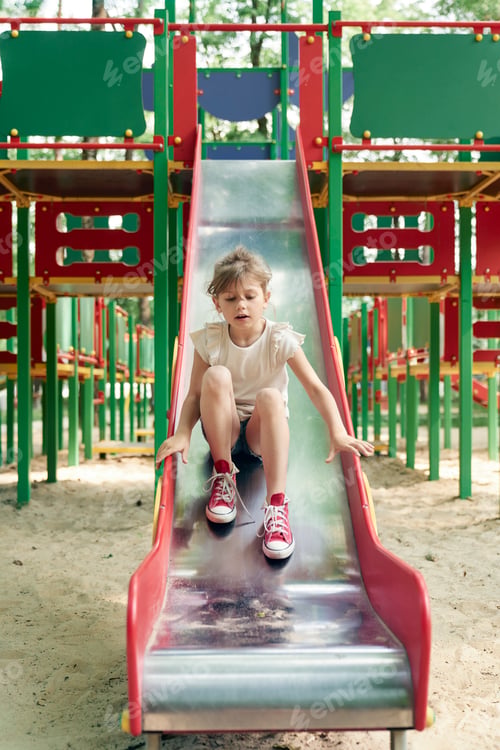 Preview: Caucasian girl playing at sliding in summer day