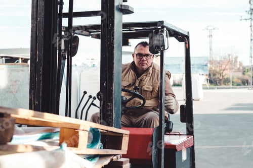 Preview: Real worker driving a forklift looking at the camera with a confident attitude