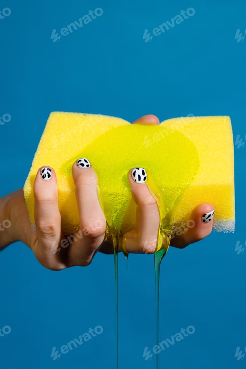 Preview: Closeup photo of hand and sponge with cleaning gel isolated over blue wall