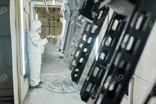 Preview: Man painting metal products with spray gun