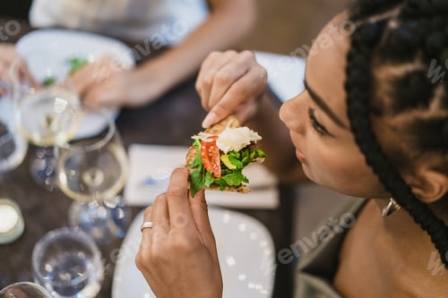 Preview: Woman eating a slice of pizza in restaurant - Closeup of hands holding fresh food