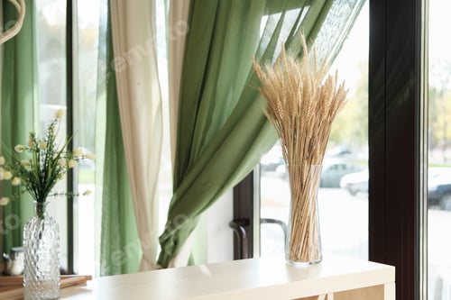 Preview: interior of cafe or terrace with natural decor. ear of wheat in a glass vase on light wooden table
