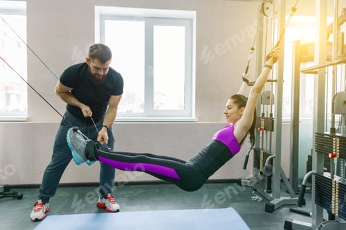Preview: Young woman doing rehabilitation exercises with personal instructor using kinesi machine