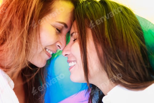 Preview: Happy gay lesbian couple celebrating pride event under rainbow flag - Lgbt family love relationship