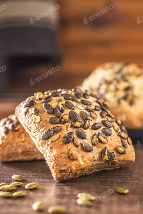 Preview: Whole grain bun with pumpkin seeds on wooden table.
