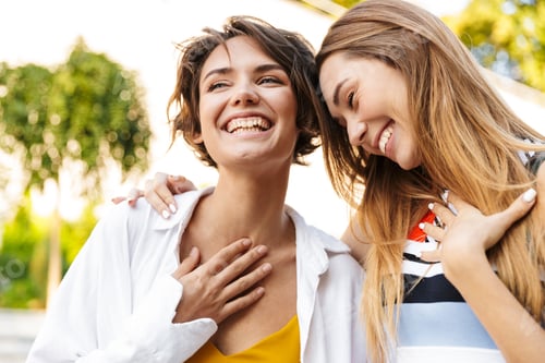 Preview: Photo of two beautiful women laughing while walking in green park