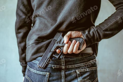 Preview: A man holding a gun on his back.The gunman held his gun behind him. Crime Concept. Criminality.