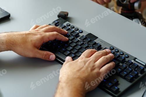 Preview: Hands typing on a modern keyboard in a workspace setting during daylight hours
