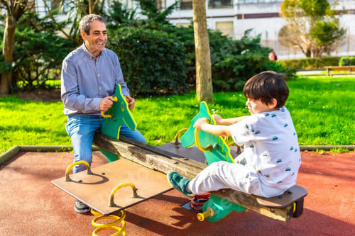 Preview: Grandfather and grandson playing on a seesaw in a playground